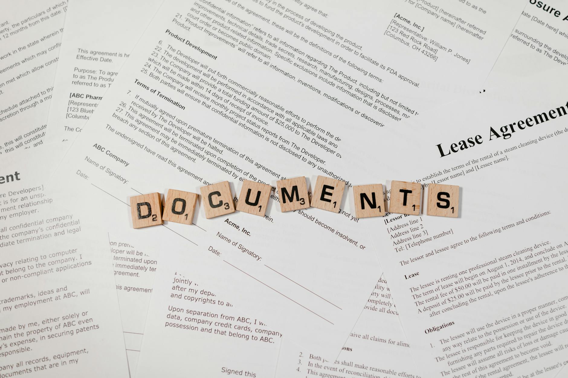 Top view of scrabble tiles spelling DOCUMENTS on various contracts and agreements.